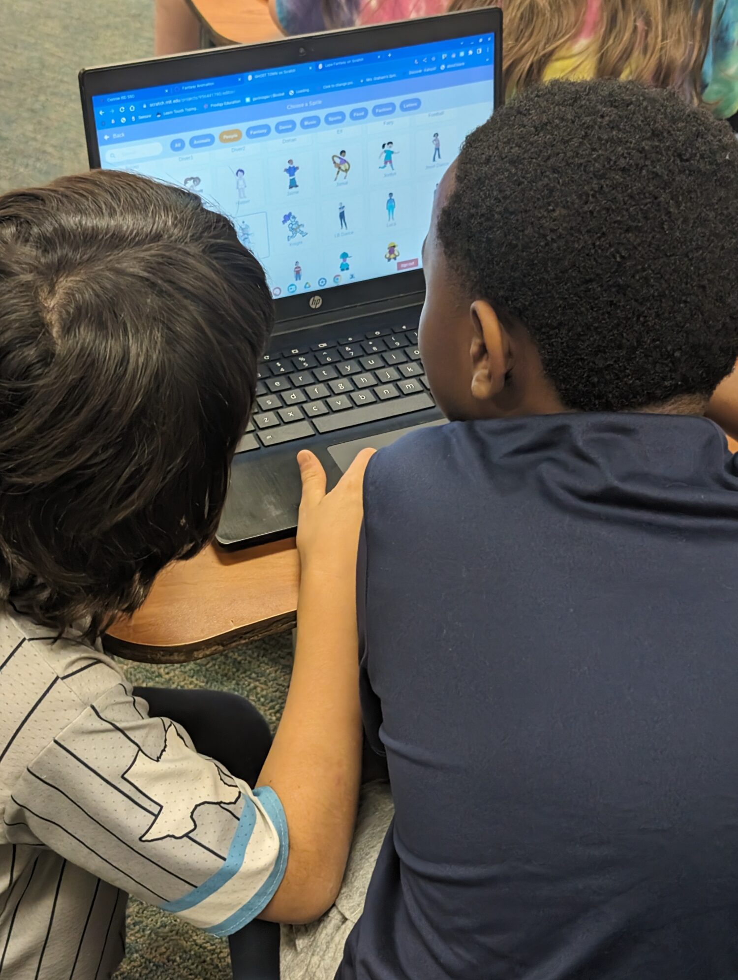 Picture over the shoulder of two boys looking at a computer screen.