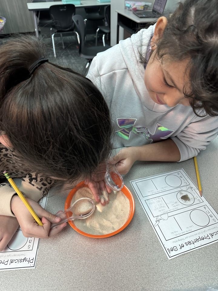Two Gordon-Reed Elementary students use a magnifying glass to see different soils close up.