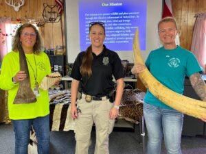 Coach Dawn Davis (left) and Coach Venessa Wallace (right) stand with a guest presenter from the office of law enforcement of the U.S. Fish and Wildlife Service.